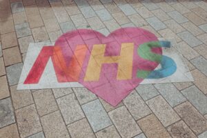 NHS multi-colour logo on an outside floor featuring a heart